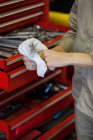 Abgeschnittenes Bild einer Mechanikerin, die sich in der Werkstatt mit Serviette die Hand abwischt — Stockfoto