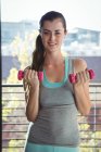 Portrait of woman lifting dumbbells in the gym — Stock Photo