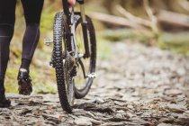 Low section of biker walking with bicycle on pathway — Stock Photo