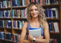 Portrait of woman holding digital tablet in library — Stock Photo