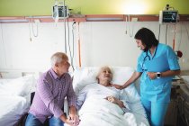 Casal sênior interagindo com enfermeira no hospital — Fotografia de Stock
