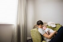 Мама держит ребенка, пока спит в гостиной на дому — стоковое фото