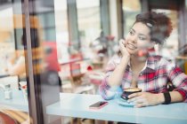 Smiling thoughful young woman sitting at restaurant — Stock Photo