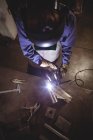 High angle view of Female welder working on piece of metal in workshop — Stock Photo