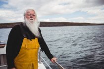 Nachdenklicher Fischer, der vom Fischerboot auf das Meer blickt — Stockfoto