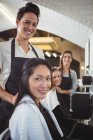 Retrato de cabeleireiros sorridentes trabalhando em clientes no salão de cabeleireiro — Fotografia de Stock