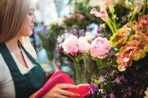 Жіночий флорист поливає воду у квітковій вазі в квітковому магазині — стокове фото
