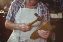 Mid section of shoemaker hammering on a shoe in workshop — Stock Photo