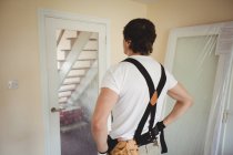 Carpinteiro olhando para a porta reparada em casa — Fotografia de Stock