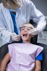 Стоматолог досліджує молодого пацієнта з інструментами в стоматологічній клініці — стокове фото