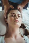 Мужской физиотерапевт делает женскому пациенту массаж головы в клинике — стоковое фото