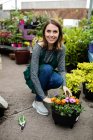 Portrait of happy female florist with potted plants in garden centre — Stock Photo