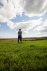 Comprimento total do homem em pé no campo gramado contra o céu nublado — Fotografia de Stock