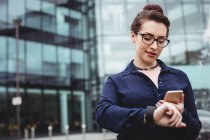 Бізнес-леді, використовуючи мобільний телефон за межами офісної будівлі — стокове фото