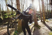 Мужской горный велосипедист с велосипедом в лесу — стоковое фото
