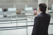 Empresario usando teléfono móvil en terminal del aeropuerto - foto de stock