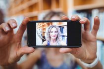 Schöne Frau macht Selfie mit Handy in Bibliothek — Stockfoto