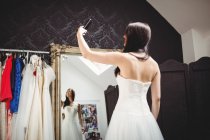 Женщина делает селфи, примеряя свадебное платье в студии — стоковое фото