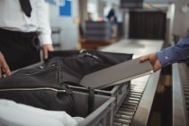 Человек кладет ноутбук в лоток для проверки безопасности в аэропорту — стоковое фото
