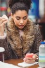 Молода жінка використовує мобільний телефон, маючи хліб в ресторані — стокове фото