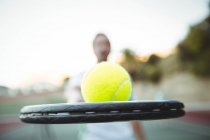 Крупный план теннисного мяча и ракетки, проводимых игроком на корте — стоковое фото