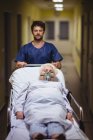 Мальчик-палата толкает старшего пациента на носилки в больничном коридоре — стоковое фото