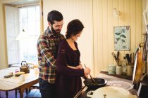 Объятие пара готовит еду вместе на кухне дома — стоковое фото
