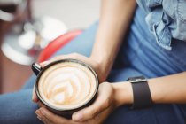Mittelteil der Frau mit Kaffeetasse im Restaurant — Stockfoto
