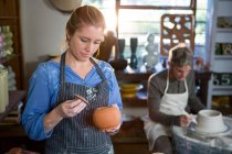 Ceramista donna che controlla pentola in laboratorio di ceramica — Foto stock