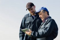 Travailleurs agricoles discuter sur tablette numérique contre ciel clair — Photo de stock