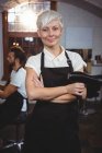 Portrait of female hairdresser standing with arms crossed at salon — Stock Photo