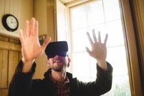 Primer plano del joven haciendo gestos mientras usa el simulador de realidad virtual en casa - foto de stock