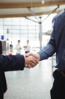 Businessmen shaking hands in airport terminal — Stock Photo