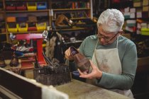 Зрелый сапожник осматривает обувь в мастерской — стоковое фото