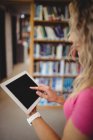 Mujer usando tableta digital en la biblioteca - foto de stock