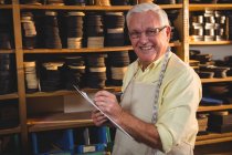 Senior-Schuhmacher schreibt in Werkstatt auf Klemmbrett — Stockfoto