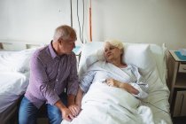 Старший чоловік втішає старшу жінку в лікарні — стокове фото
