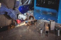 Cropped image of welder cutting metal with electric tool in workshop — Stock Photo