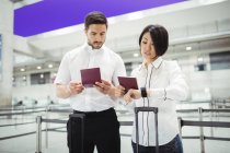 Business man and woman checking their passports in airport terminal — Stock Photo