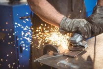 Cropped image of welder cutting metal with electric tool in workshop — Stock Photo