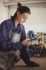 Женщина-сварщик с помощью цифрового планшета в мастерской — стоковое фото