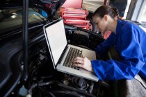 Mechanikerin mit digitalem Tablet bei der Wartung des Automotors in der Werkstatt — Stockfoto