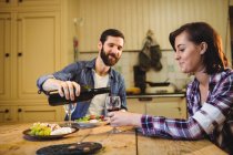 Homme versant du vin dans un verre à la femme à la maison — Photo de stock