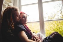 Young hipster couple sitting by window at home — Stock Photo