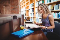 Woman sitting and reading book in library — Stock Photo