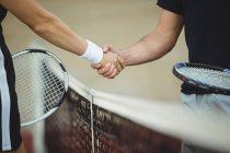 Mid section of tennis players shaking hands in court before match — Stock Photo