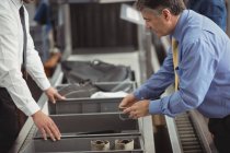 Homem colocando relógio na bandeja para verificação de segurança no aeroporto — Fotografia de Stock