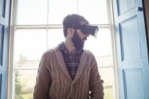 Giovane uomo con occhiali virtuali a casa vicino alla finestra — Foto stock