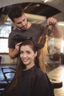 Mujer secándose el pelo con secador de pelo en la peluquería - foto de stock