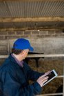 Вид збоку фермера, використовуючи цифровий планшет, огорожа на сарай — стокове фото
